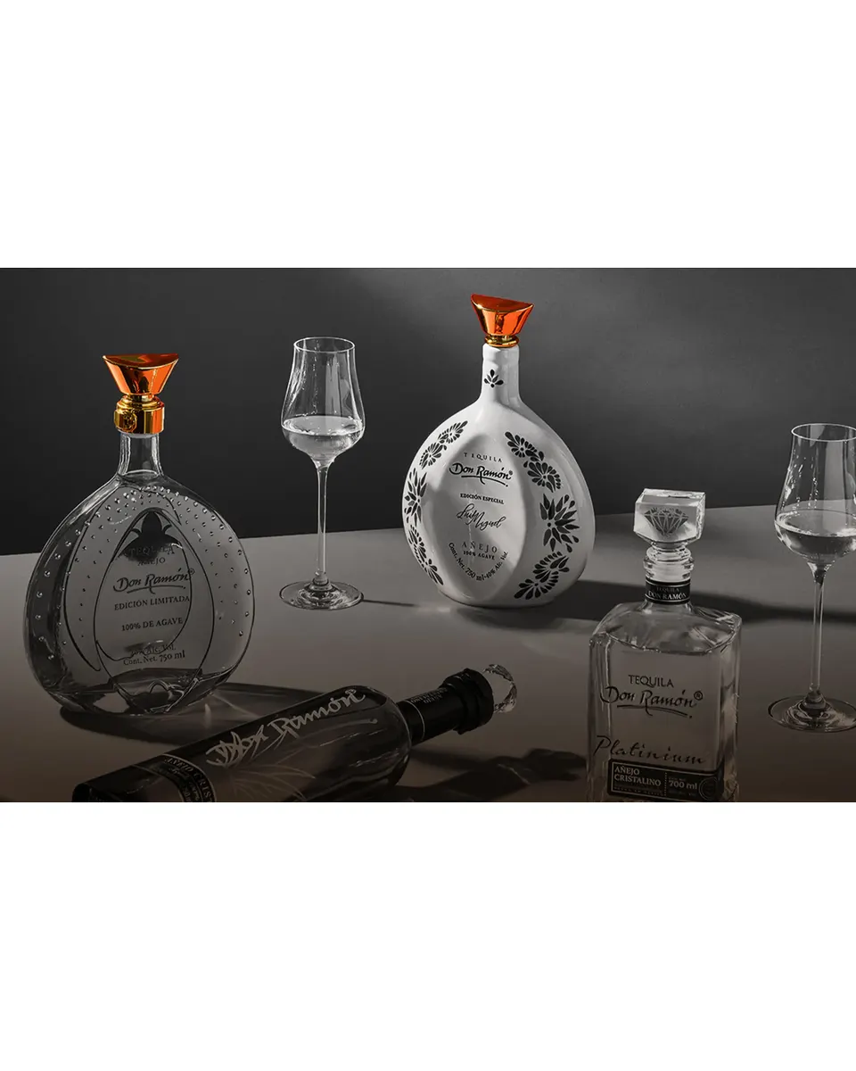 Studio still life of Tequila Don Ramón bottles and glassware on a dark surface